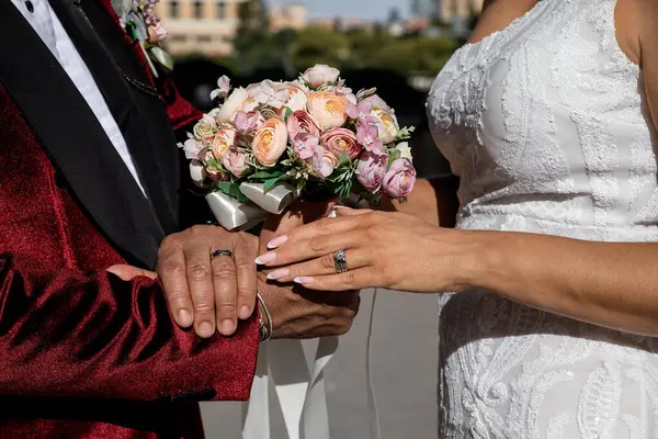 Gelin ve damat, törenden hemen sonra el ele tutuşup evlilik yüzüklerini gösteriyorlar.