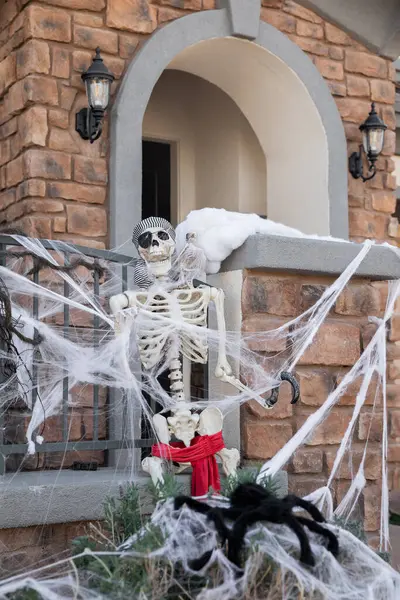 Korkunç Cadılar Bayramı iskeleti ve evin ön bahçesinde siyah örümcek sonbahar titreşimleri ve sonbahar tatili konsepti.