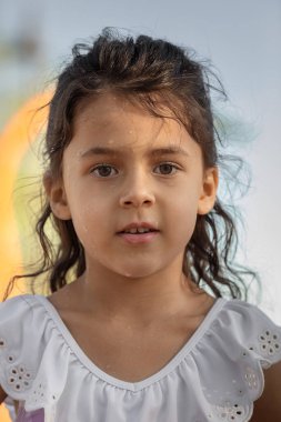 Gün batımında ıslak yüzlü ve kameraya bakan küçük kız yaz tatilleri ve çocukluk anıları konsepti - görüntü