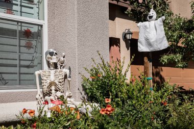 Fall and Halloween decoration adorn a haunted house front yard - Image