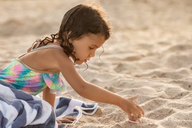 Little child girl playing with sand at the beach at summer sunset in Miami, childhood memories and active kids concept - Image