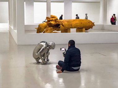 Paris Fransa - 04.06.2022: Pompidou merkezindeki çağdaş sanat müzesinin zemininde oturan ve bükülen bir heykelin cep telefonuyla fotoğraf çeken sıradan giyinmiş bir adamın dikiz görüntüsü