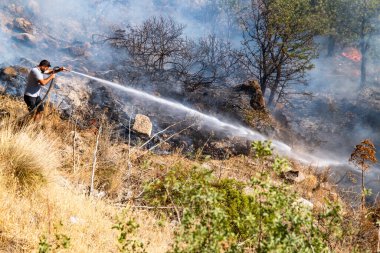 Bodrum, Türkiye, 08.08.2023: Sivil adam tehlikeli alev dilleri ve Ege kıyılarını kaplayan yangın dumanına karşı mücadele ediyor. Fotokopi alanı ile felaket arkaplanı. Ekolojik küresel ısınma, iklim değişikliği