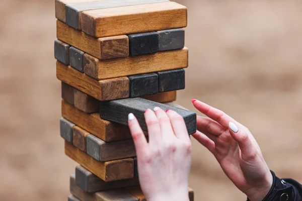 Jenga tower game in nature. Close-up shot of Jenga wooden block game. Concept of risk management. High quality photo