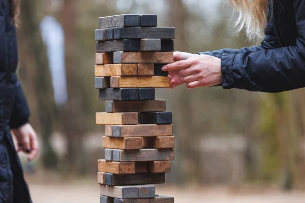 Jenga tower game in nature. Close-up shot of Jenga wooden block game. Concept of risk management. High quality photo