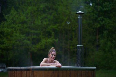 Genç ve mutlu bir kadın jakuzide dinleniyor. Ormanların dışındaki sağlık merkezinin tadını çıkarıyorum. Sıcak banyo spa merkezi. Yüksek kalite fotoğraf