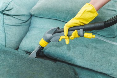 Modern elektrikli süpürge tutan hizmetçi ve profesyonel deterjanla kirli kanepeyi temizleyen kadın. Ev kavramında profesyonel bahar temizliği. Yüksek kalite fotoğraf