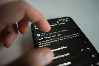 Adam internet dükkanlarında takılıyor ve kara Cuma anlaşmalarını inceliyor. Yüksek kalite fotoğraf. Londra, Birleşik Krallık - 13 Kasım 2024