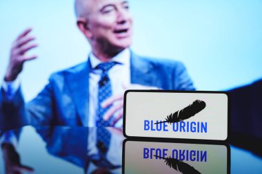 Arka planda mavi menşeili logo ve Jeff Bezos var. 6 Aralık 2024