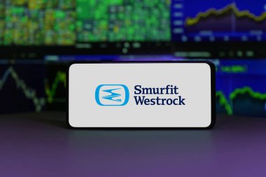 Smurfit Kappa logo displayed on a smartphone screen with stock market charts in the background. January 2, 2025 clipart