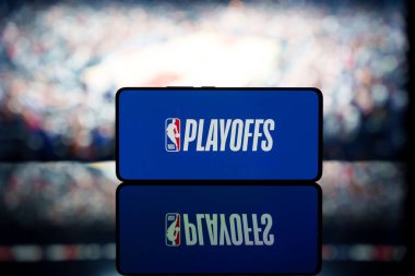  NBA playoff 'larının logosunu bulanık bir basketbol sahasının arka planında gösteren bir akıllı telefon. 13 Ocak 2025