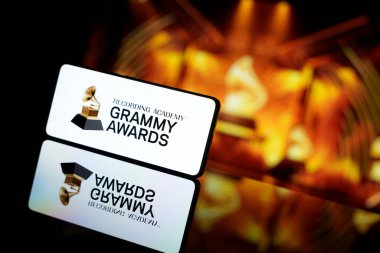 Grammy Ödülleri logosunu bulanık ödül töreninin arka planında gösteren bir akıllı telefon. 13 Ocak 2025