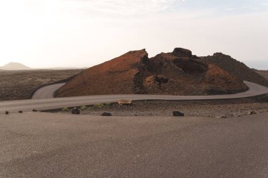 Lanzarote 'de volkanik bir manzara, kırmızı kum, lav kayaları ve sisli bir gökyüzünün altındaki dağlar. Yüksek kalite fotoğraf