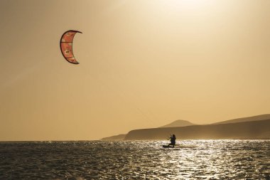 Gün batımında uçurtma silueti okyanusta, gökyüzünde bir uçurtmayla. Yüksek kalite fotoğraf