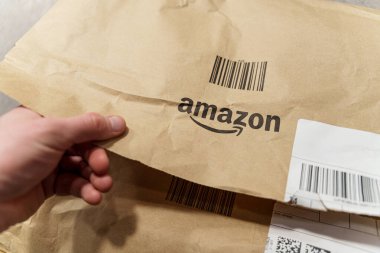 Bir kişinin çevrimiçi alışveriş yapmanın ve teslimat almanın heyecanını ve beklentilerini vurgulayan bir Amazon paketi açması. 27 Ocak 2025
