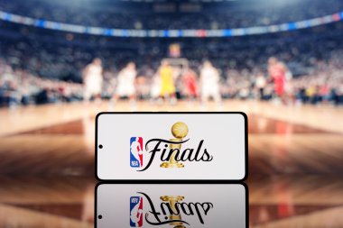 NBA Finalleri logosunda bulanık bir basketbol sahası ve arka planda oyuncular olan akıllı telefon. Basketbol şampiyonası ve spor etkinliği konsepti. 17 Mart 2025