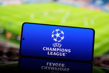 Arka planda bulanık bir futbol stadyumu bulunan UEFA Şampiyonlar Ligi logosunu gösteren akıllı telefon. Avrupa futbol yarışması ve spor etkinliği konsepti. 17 Mart 2025
