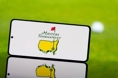 Arkasında bulanık golf topu ve yeşil alan olan Masters Turnuvası logosunu gösteren akıllı telefon. Profesyonel golf şampiyonluğu konsepti. 17 Mart 2025