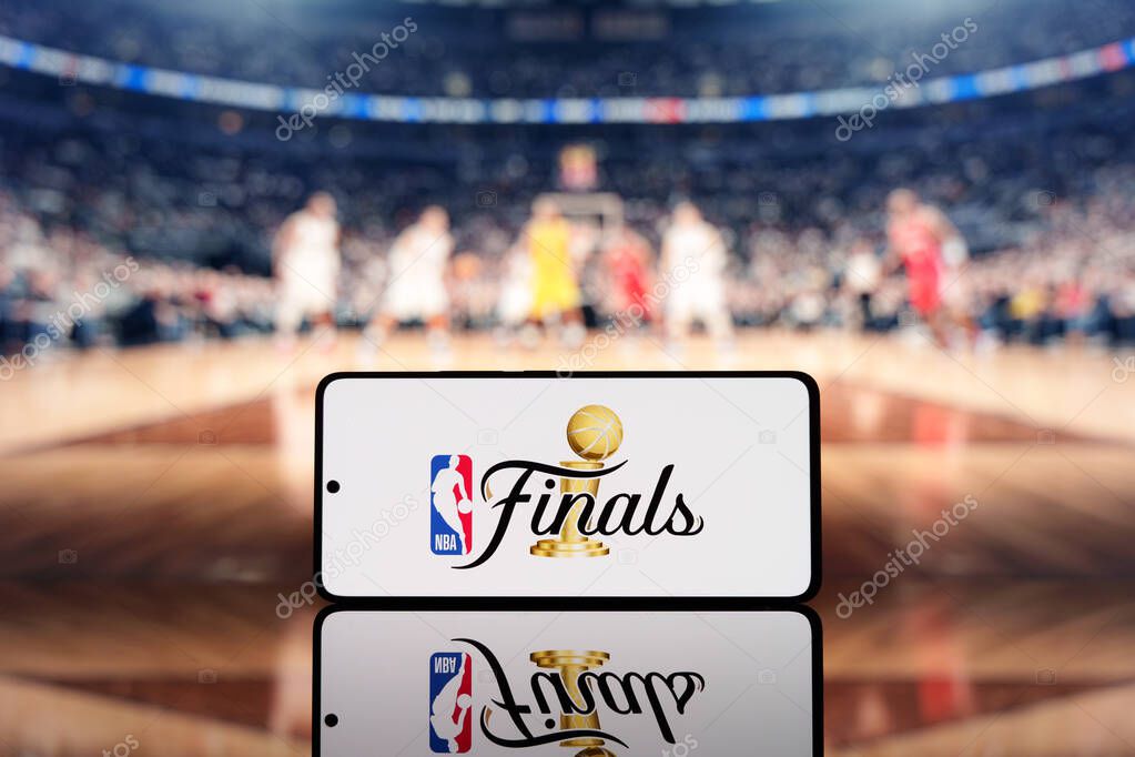 Smartphone displaying NBA Finals logo with a blurred basketball court and players in the background. Basketball championship and sports event concept. March 17, 2025