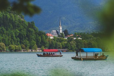 Arka planda Slovenya 'daki St. Martin Kilisesi' nin bulunduğu Bled Gölü 'ndeki geleneksel pletna tekneleri. Yüksek kalite fotoğraf