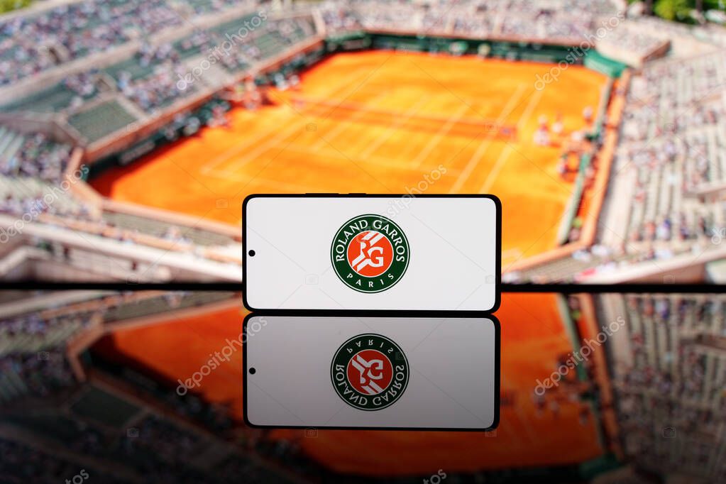 Smartphone displaying the Roland Garros logo with a blurred clay tennis court in the background. Paris Grand Slam tournament concept. March 17, 2025