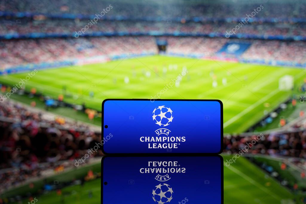 Smartphone displaying UEFA Champions League logo with a blurred soccer stadium in the background. European football competition and sports event concept. March 17, 2025