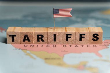  Tahta bloklar TARIFFS sözcüğünü ABD haritasına yerleştirilmiş küçük bir ABD bayrağı ile heceliyorlar. Yüksek kalite fotoğraf