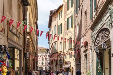Lucca, İtalya 'da eski binalar ve yürüyen turistlerle dolu dar bir cadde. 17 Mayıs 2025