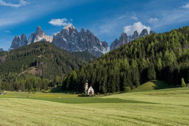 Ranui 'deki küçük St. John Kilisesi, Val di Funes' da Geisler Dağı tepeleri arka planda ve mavi gökyüzünün altındaki yeşil çayır. Yüksek kalite fotoğraf