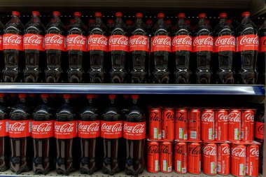 Coca Cola şişeleri ve kutuları süpermarketin rafında düzgünce dizilmiş. Yüksek kalite fotoğraf
