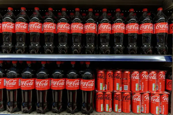 Coca Cola şişeleri ve kutuları süpermarketin rafında düzgünce dizilmiş. Yüksek kalite fotoğraf