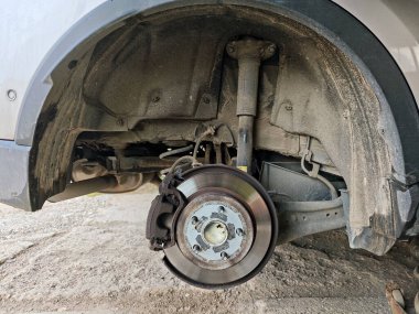 disc brake assembly with the wheel removed, showing the caliper, polished rotor, and wheel hub with mounting studs. High quality photo