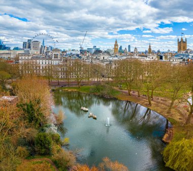 Göl, Londra 'nın merkezindeki St. James' s Park 'ın havadan görünüşü, Londra Gözü, Big Ben ve Westminster ile ikonik bir gökyüzü. Şehir simgeleri ve doğal manzaranın harika bir karışımı.