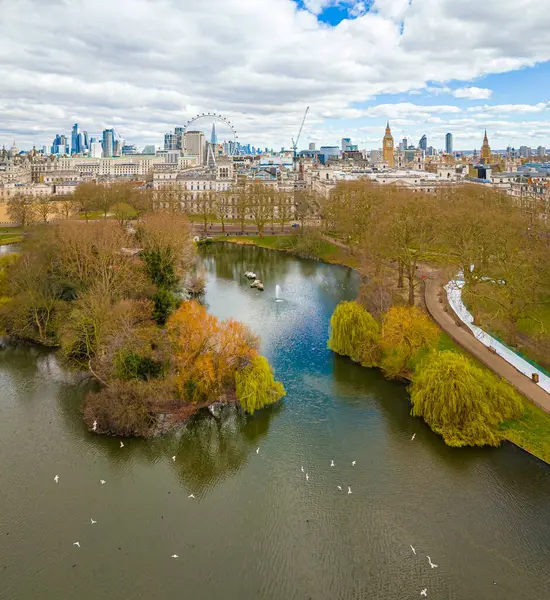 Göl, Londra 'nın merkezindeki St. James' s Park 'ın havadan görünüşü, Londra Gözü, Big Ben ve Westminster ile ikonik bir gökyüzü. Şehir simgeleri ve doğal manzaranın harika bir karışımı.