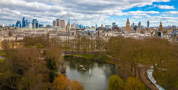 Göl, Londra 'nın merkezindeki St. James' s Park 'ın havadan görünüşü, Londra Gözü, Big Ben ve Westminster ile ikonik bir gökyüzü. Şehir simgeleri ve doğal manzaranın harika bir karışımı.