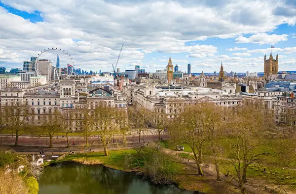 Göl, Londra 'nın merkezindeki St. James' s Park 'ın havadan görünüşü, Londra Gözü, Big Ben ve Westminster ile ikonik bir gökyüzü. Şehir simgeleri ve doğal manzaranın harika bir karışımı.