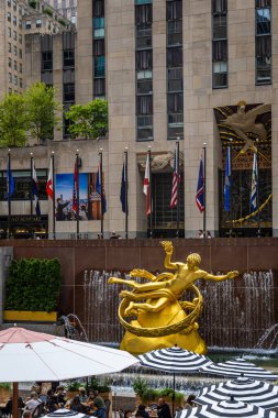 Manhattan, New York 'taki Rockefeller Center' ın uzun gökdelenleri, bayrakları ve turistleri var. Seyahat, turizm, iş, kültür, alışveriş ve ikonik New York eğlencelerini temsil eder