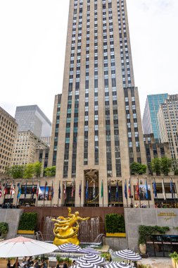 Manhattan, New York 'taki Rockefeller Center' ın uzun gökdelenleri, bayrakları ve turistleri var. Seyahat, turizm, iş, kültür, alışveriş ve ikonik New York eğlencelerini temsil eder