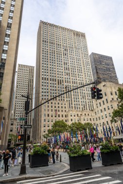 Manhattan, New York 'taki Rockefeller Center' ın uzun gökdelenleri, bayrakları ve turistleri var. Seyahat, turizm, iş, kültür, alışveriş ve ikonik New York eğlencelerini temsil eder