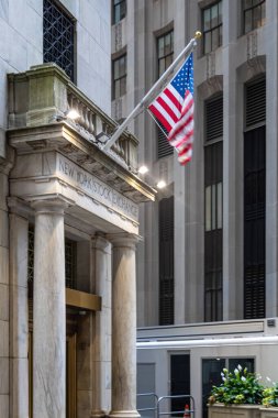 Manhattan Financial District Wall Street 'teki New York Borsası' nın dışı gökdelenler ve bayraklarla çevrili. Finans, ekonomi, iş, ticaret ve ikonik NYC simgesini temsil ediyor.