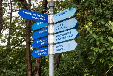 Doğu Nehri boyunca uzanan ikonik Brooklyn Köprüsü. Arka planda Manhattan silueti ve oradan geçen bir tekne var. Seyahat, turizm, mimari ve New York Şehri yaşam tarzı temaları için mükemmel.