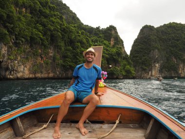 young man in a longtail boat in thailand