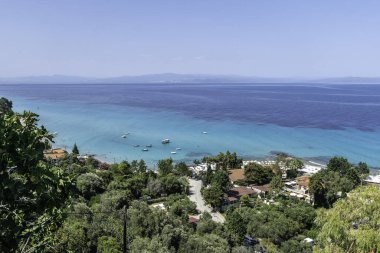 Afytos, Yunanistan, 17 Temmuz 2023. Bir tepenin üstünde yer alan Afitos köyü, aşağıda popüler bir plaj bulunan Toronean Körfezi 'ne bakıyor..