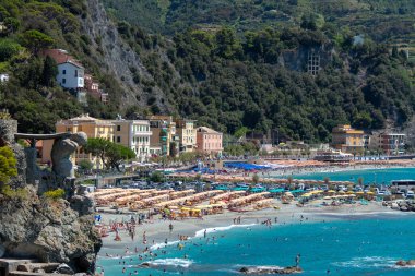 Monterosso, İtalya, 27 Temmuz 2023. Dev tanrı Poseidon 'un ya da Neptün' ün heykelinin önündeki plaj ve şemsiyeler.