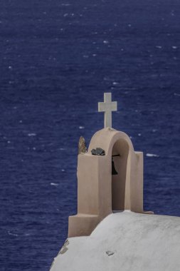 Santorini, Yunanistan, 5 Mayıs 2024. Oia. Denize bakan beyaz haçı olan bir kilise çanı.