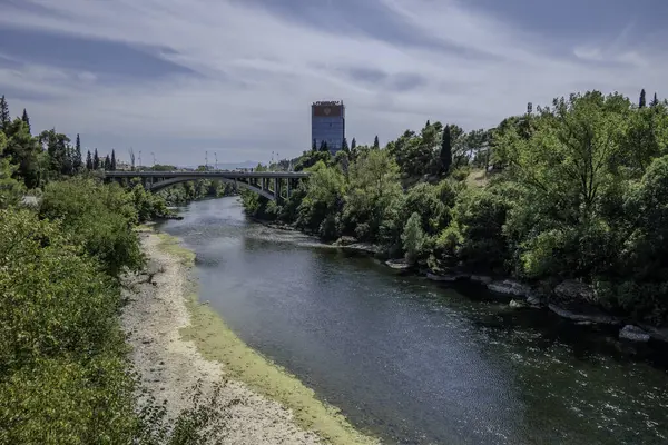 stock image Podgorica, Montenegro, August 5, 2024.Ribnica River and Montenegro Flag on Bemax Building