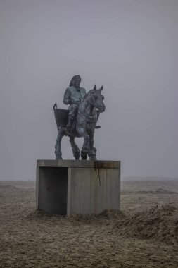 Oostduinkerke, Belgium, December 28, 2024. Landscape with a fisherman statue in the fog. clipart