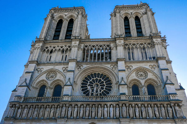 Париж, Франция, 6 марта 2025 года. Нотр-Дам. Фасад с розовым окном и статуями.