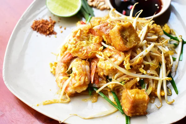 レモンとソース タイスタイル アジア料理と美味しいエビとホワイトディッシュで分離されたパッドタイ麺 — ストック写真