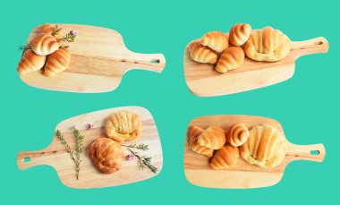 Tahta kesme tahtasına izole edilmiş peynirli kruvasan, yeşil arka planda gölge yok, ev yapımı tatlı.